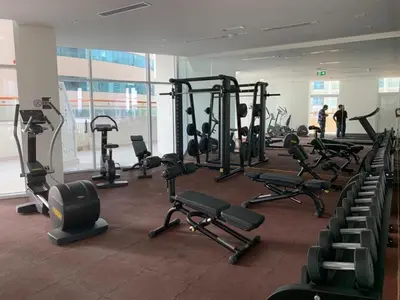 a gym with several tread machines and people in the background at Millennium Binghatti Residence - Business Bay - Homeyvillas in Dubai
