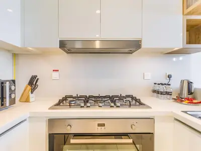 a white kitchen with a stove top oven at TRPS - Downtown Views II Tower 2, Downtown Dubai - 3BR plus Maids - Burj Khalifa View - Walk to Dubai Mall in Dubai