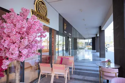 a lobby with pink flowers and tables and chairs at Stylish 1-Bedroom Apartment with Modern Interior in Dubai