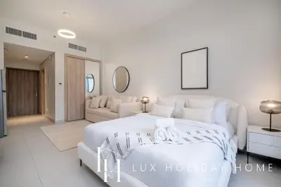 a white bedroom with a large bed and a couch at LUX Dubai Hills Sway Studio in Dubai