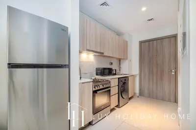 a kitchen with a refrigerator and a stove top oven at LUX Dubai Hills Sway Studio in Dubai