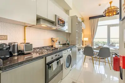 a kitchen with a washer and dryer and a table at Studio Near Dubai Butterfly Garden, 18 Mins Drive From Mall of Emirates, Miraclz Tower, Arjan By Deluxe Holiday Homes in Dubai