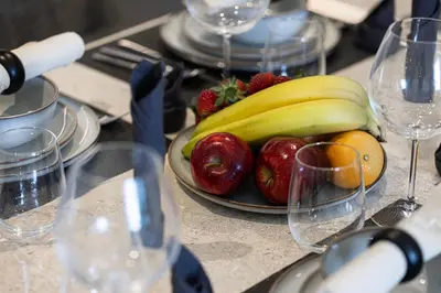 a plate of fruit on a table with wine glasses at Sky-High Luxury 2BR Burj View Walk Dubai Mall in Dubai