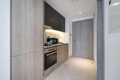 a kitchen with wooden cabinets and a stove top oven at Restay Homes - Chic Studio in JVC - Pool Views in Dubai