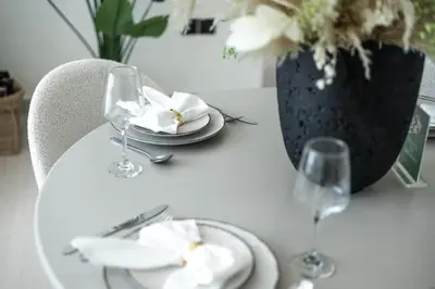 a table with a plate and glasses and a vase with flowers at New 2BR with Jacuzzi and Big Balcony In City Center in Dubai