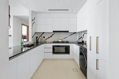 a white kitchen with a stove and a dishwasher at New 2BR with Jacuzzi and Big Balcony In City Center in Dubai