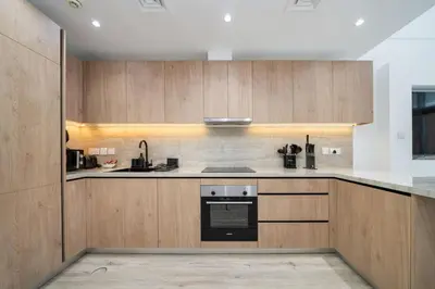 a kitchen with wooden cabinets and a stove at Luxury JVC 2 Bed Duplex with Private Pool and Jacuzzi in Dubai