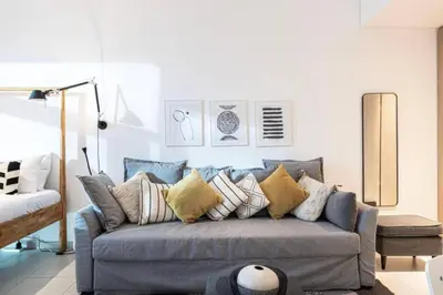 a living room with a blue couch with pillows at Elegant Cozy Studio Canal View in Dubai