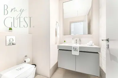 a white bathroom with a sink and a mirror at Peerless 3BR Beachfront Living in Sunrise Bay in Dubai