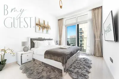 a white bedroom with a bed and a large window at Peerless 3BR Beachfront Living in Sunrise Bay in Dubai