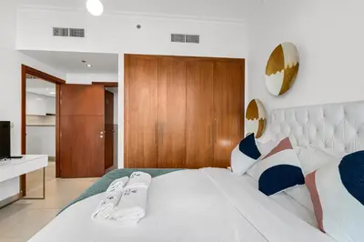 a bedroom with a large white bed with wooden cabinets at Burj Vista - Prime Downtown Dubai in Dubai