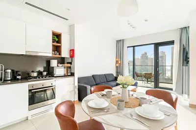 a kitchen and living room with a table and chairs at Panoramic Marina 1BR City Skyline Views with Balcony, Pool & Gym Access in Dubai