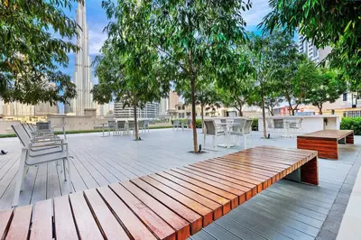 a wooden bench on a deck with tables and chairs at Elegant 1BR Near Burj Khalifa and Dubai Mall with Pool, Balcony, & Gym in Dubai