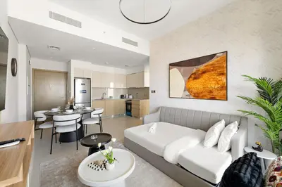 a living room with a white couch and a kitchen at Elegant 1BR Near Burj Khalifa and Dubai Mall with Pool, Balcony, & Gym in Dubai