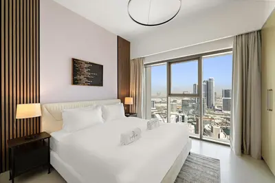 a bedroom with a large white bed and a large window at Elegant 1BR Near Burj Khalifa and Dubai Mall with Pool, Balcony, & Gym in Dubai
