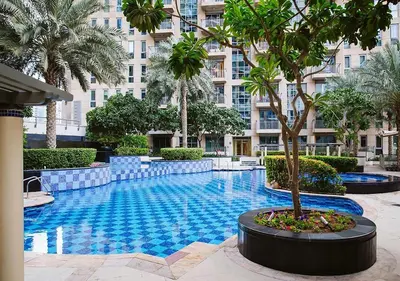 a swimming pool with a palm tree in front of a building at Stunning 1 BR Apartment Walk to Burj Khalifa & Dubai mall in Dubai