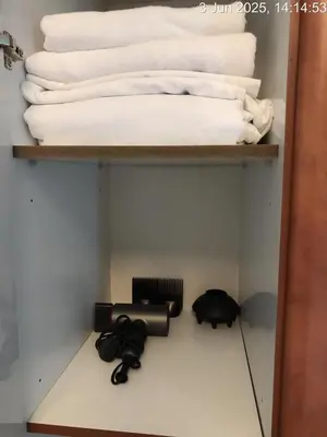 a shelf with towels and a hair dryer and a cat on it at Cozy 1 Bed aprt in Marina Diamond 1 Tower in Dubai