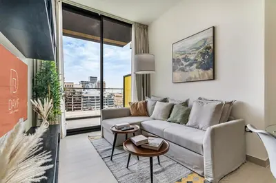 a living room with a couch and a large window at DAYF-AMB Brand New Cozy 1 Bed up to 4 Guests in Dubai