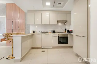 a white kitchen with white cabinets and appliances at Lovely Studio in JVC with Summer Offer in Dubai