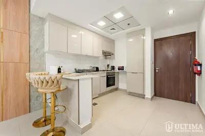 a kitchen with white cabinets and a stool in it at Lovely Studio in JVC with Summer Offer in Dubai