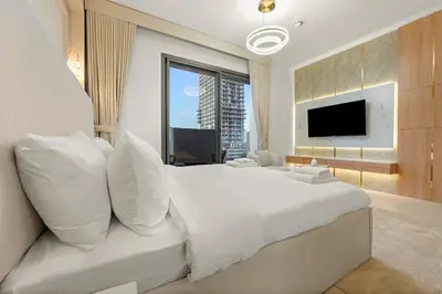 a bedroom with a large white bed with a flat screen tv at Lovely Studio in JVC with Summer Offer in Dubai