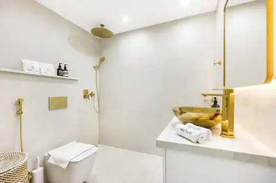 a white bathroom with a toilet and a sink at Spacious 2BR with Balcony, Stunning Burj Views & Steps from Bay Avenue Park in Dubai