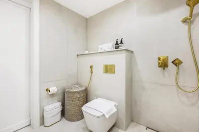a white bathroom with a toilet and a shower at Spacious 2BR with Balcony, Stunning Burj Views & Steps from Bay Avenue Park in Dubai