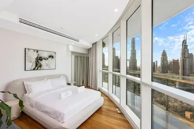 a bedroom with a white bed and large windows at Spacious 2BR with Balcony, Stunning Burj Views & Steps from Bay Avenue Park in Dubai