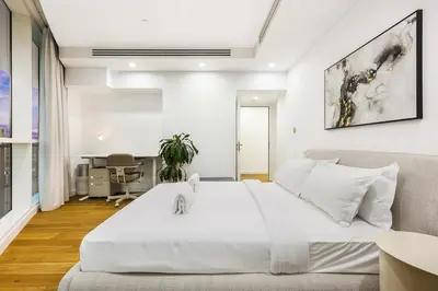 a bedroom with a large white bed and a desk at Spacious 2BR with Balcony, Stunning Burj Views & Steps from Bay Avenue Park in Dubai