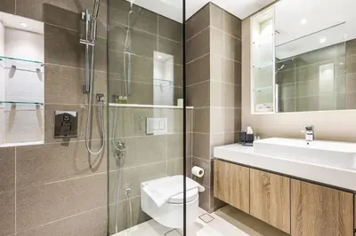 a bathroom with a shower and a toilet and a sink at Stylish Dubai Marina 2BR with Balcony, Pool, Gym Walk to Marina Walk & JBR in Dubai