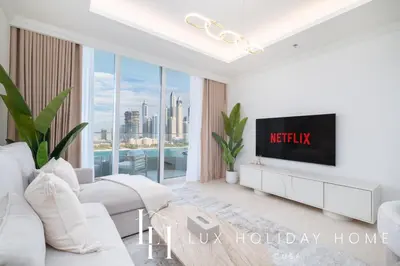 a living room with white furniture and a tv at LUX The Palace Beach Suite in Dubai