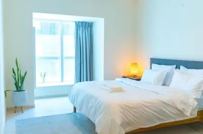 a bedroom with a large white bed with a window at Urban 1BHK Apartment with Sea View in Dubai