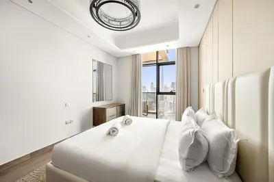 a white bedroom with a large white bed with pillows at Luxury 1BR apt with Burj Khalifa, Canal View Pool Gym Near Dubai Mall in Dubai