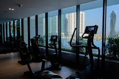 a gym with cardio equipment in a building with a large window at Kazan Homes - Lux - Studio Close to Burj Khalifa & Dubai Mall - Business Bay in Dubai