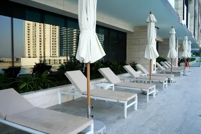 a row of white lounge chairs and umbrellas on a building at Kazan Homes - Lux - Studio Close to Burj Khalifa & Dubai Mall - Business Bay in Dubai