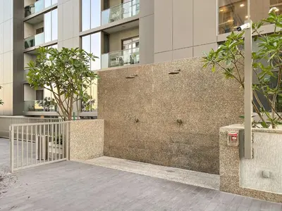 a brick wall with trees in front of a building at Elegant 1BR Stay in Sobha Creek Luxury Apartment Near Dubai Canal in Dubai