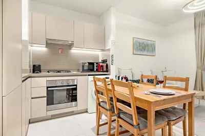 a kitchen and dining room with a wooden table and chairs at Elegant 1BR Stay in Sobha Creek Luxury Apartment Near Dubai Canal in Dubai