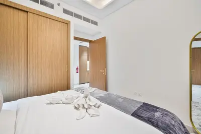 a bedroom with a large bed with white sheets at Heaven Crest Vacation Homes - One Bedroom City View Balcony in Azizi Riviera in Dubai