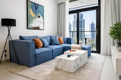 a living room with a blue couch and a table at Emaar Burj Crown - 1BR Sea View across from Burj Khalifa, walk to Dubai Mall in Dubai
