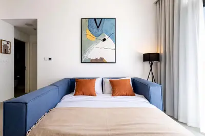 a blue couch in a room with a painting on the wall at Emaar Burj Crown - 1BR Sea View across from Burj Khalifa, walk to Dubai Mall in Dubai