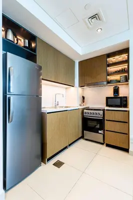 a kitchen with a stainless steel refrigerator and cabinets at Emaar Burj Crown - 1BR Sea View across from Burj Khalifa, walk to Dubai Mall in Dubai