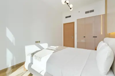 a white bedroom with a bed and a mirror at Elite apartment near Dubai Mall in Dubai