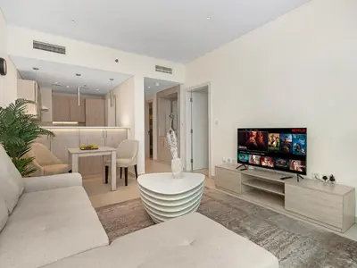 a living room with a couch and a tv at Palm Jumeirah Beachfront 1 Bedroom Apartment with Rooftop Infinity Pool and Atlantis Views in Dubai