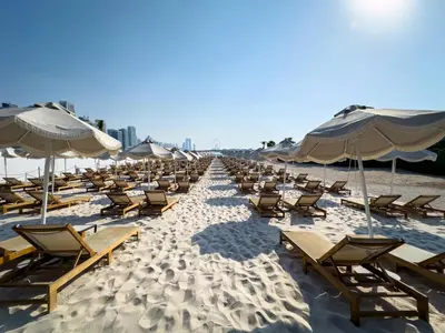 a row of chairs and umbrellas on a beach at Palm Jumeirah Beachfront 1 Bedroom Apartment with Rooftop Infinity Pool and Atlantis Views in Dubai