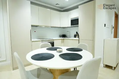a white kitchen with a white table and white chairs at Stylish 1B in Heart of Marina Near Attractions in Dubai