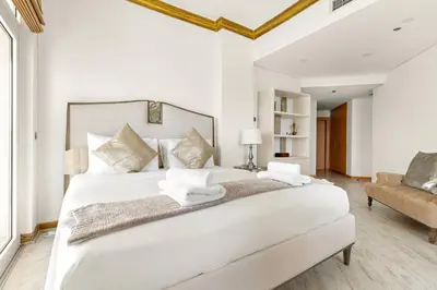 a white bedroom with a large bed and a couch at VayK - Stunning 2BR with Sea View & Beach Access in Dubai
