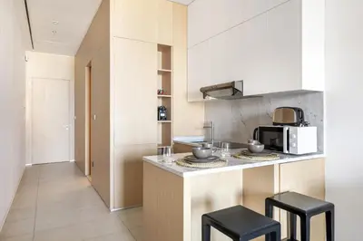 a kitchen with a counter with two stools and a microwave at VayK - Great Escape at Anantara The Palm Residences in Dubai