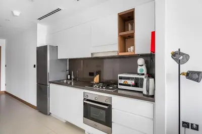 a white kitchen with a stove and a microwave at VayK - Sleek & Stylish 1BR in Vida Dubai Marina in Dubai
