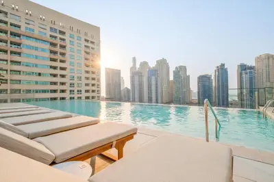 a swimming pool with chaise lounge chairs and a city skyline at VayK - Sleek & Stylish 1BR in Vida Dubai Marina in Dubai