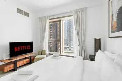 a white bedroom with two beds and a tv at VayK - Premium 2BR Stay in Dubai Marina in Dubai